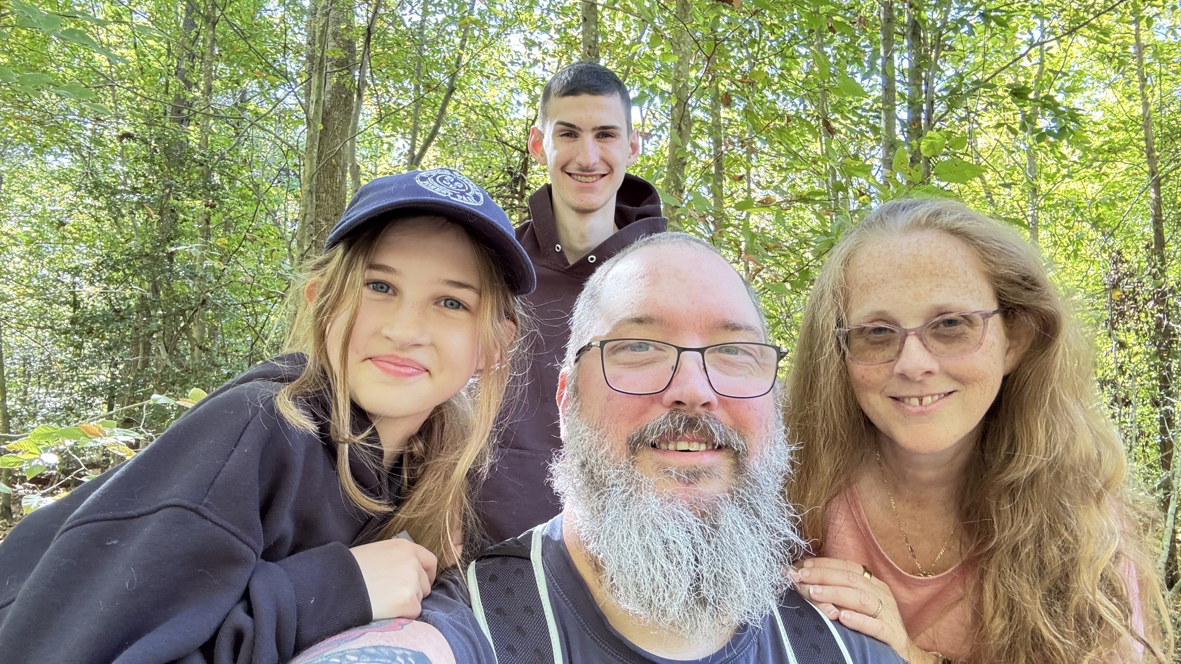 Mike with family smiling together in an outdoor wooded setting
