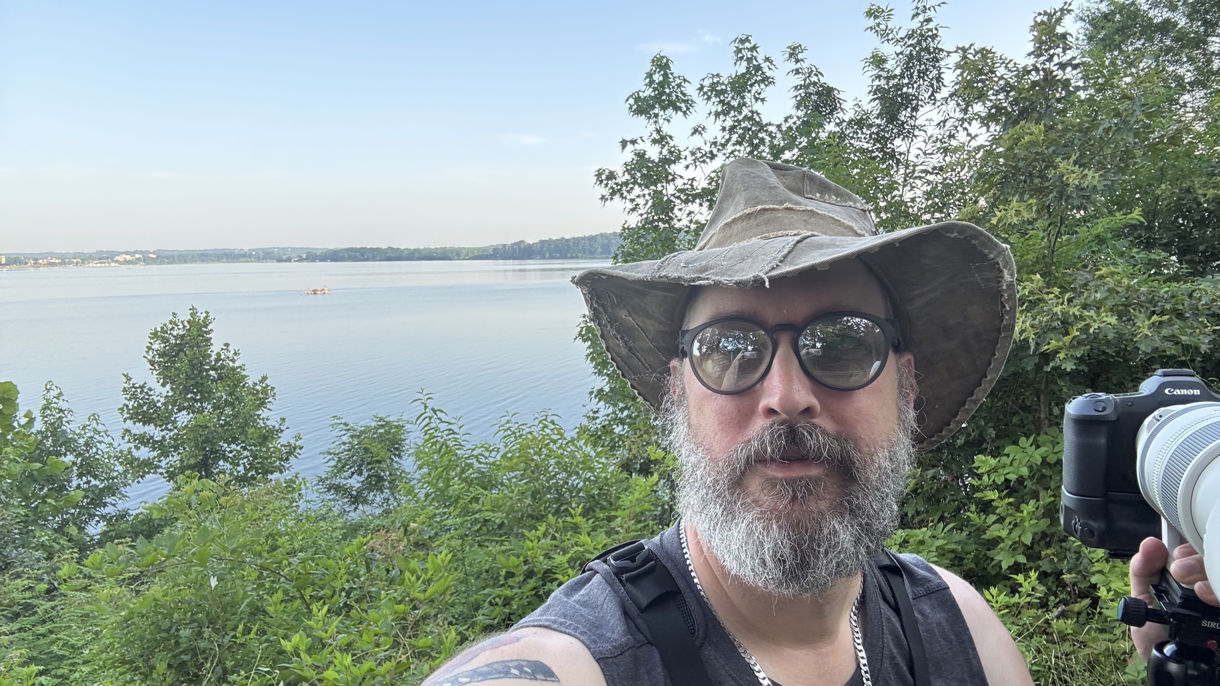 Mike wearing a wide-brimmed hat with a Canon camera near the water