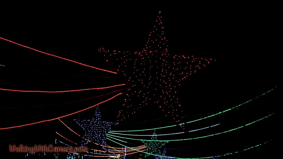 A star-shaped light display and sweeping colored strands brighten a dark night sky.