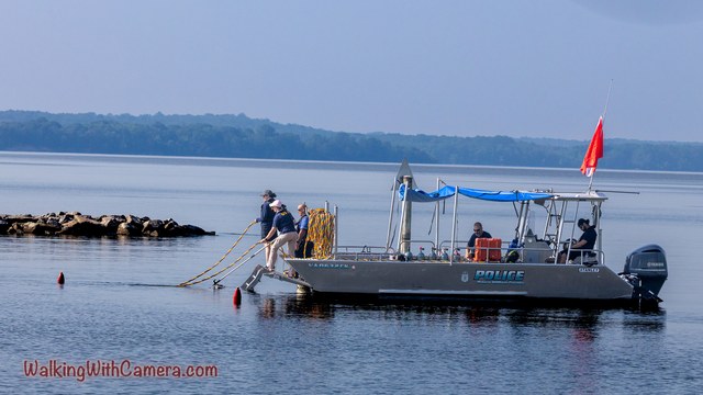 A boat with a blue canopy and red flag sits on the water with people aboard.