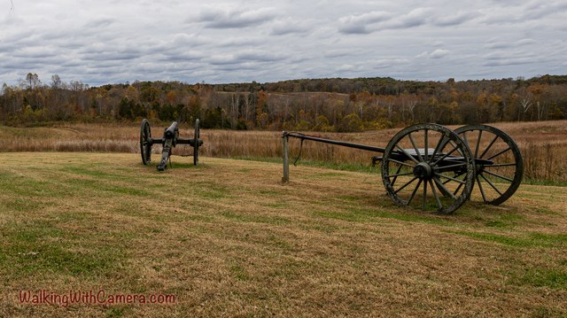 Two historic cannons stand in an open field beneath a cloudy sky.